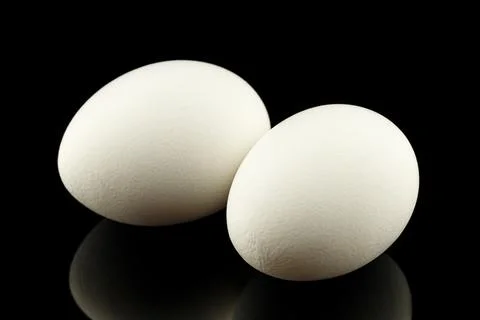 Two white eggs black background Stock Photos