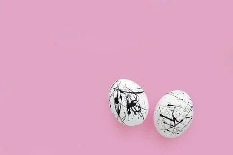 Two white eggs in black spots on a pink background with a copy of the space.  Stock Photos
