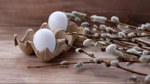 Two white eggs in box and willow branches on wooden background Stock Photos