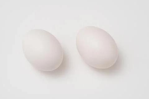 Two white eggs on white background Stock Photos