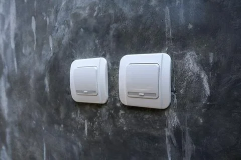 Two white electrical light switches mounted on a raw polished concrete Stock Photos