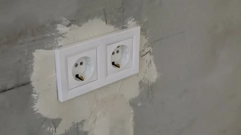 A two white electrical outlets within a plastic frame mounted on a grey Video stock 294202373