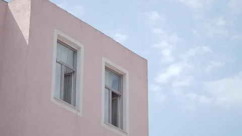 Two white framed windows in a pink building against a bright blue sky with .. Stock Footage 332210429