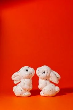 Two white glitter Easter bunnies facing each other on red background with c.. Foto stock