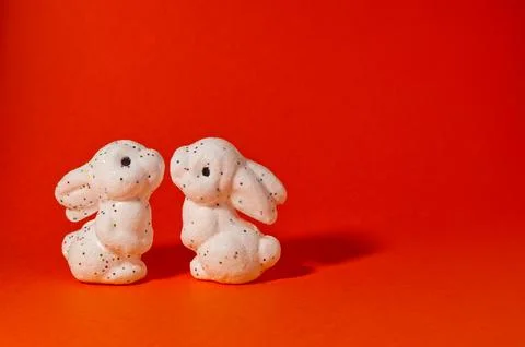 Two white glitter Easter bunnies facing each other on red background with c.. Stock Photos