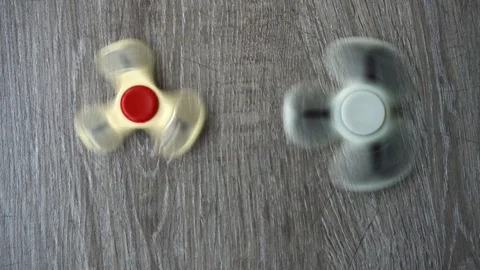 Two white hand spinner spinning on grey background or fidget spinners Stock Footage 76541158