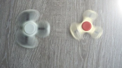 Two white hand spinner spinning on grey background or fidget spinners Stock Footage 76549387