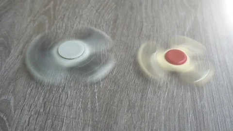 Two white hand spinner spinning on grey background or fidget spinners 動画素材 76555880