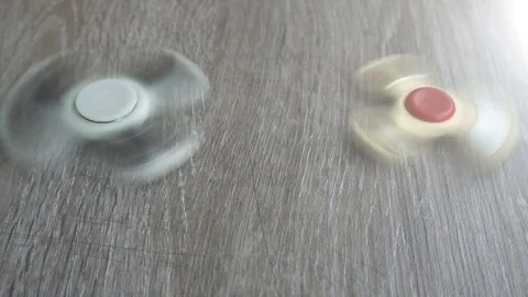 Two white hand spinner spinning on grey background or fidget spinners 스톡 동영상 76558878