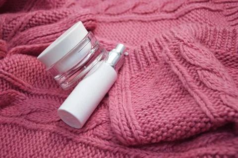 Two white jars of cream on a background of a pink knitted scarf. Winter ski.. Foto stock