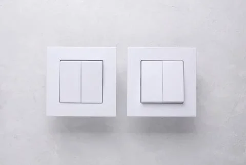 Two white light switches on a wall with a plain background Stock Photos