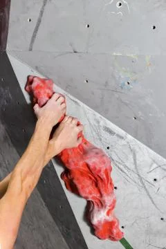 Two white man's hands are held on the oval passive hook of the climbing wall Stock Photos