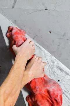 Two white man's hands are held on the oval passive hook of the climbing wall Stock Photos