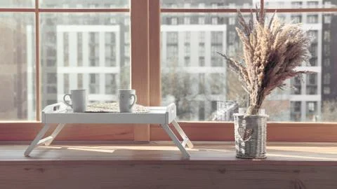 Two white mugs on Serving table with flowers vase on window sill Stock Photos