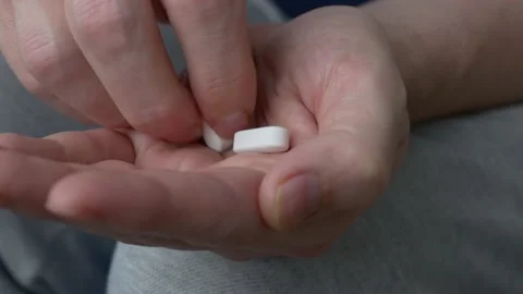 Two white oblong tablets are poured into the palm of your hand. Taking Vídeos de archivo 200038744