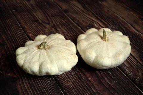 Two white pattypan squashed on dark wooden board, whole raw vegetable Stock Photos