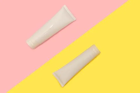 Two white plastic containers. On a pink and yellow background. Stock Photos