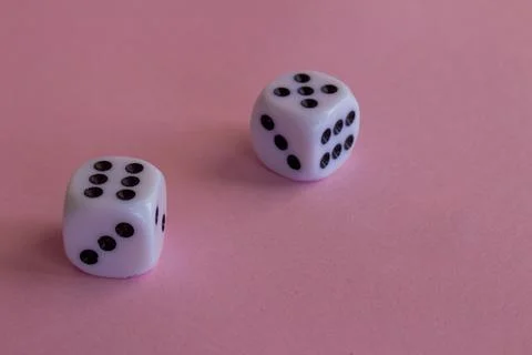 Two white plastic dice on a pink background Stock Photos
