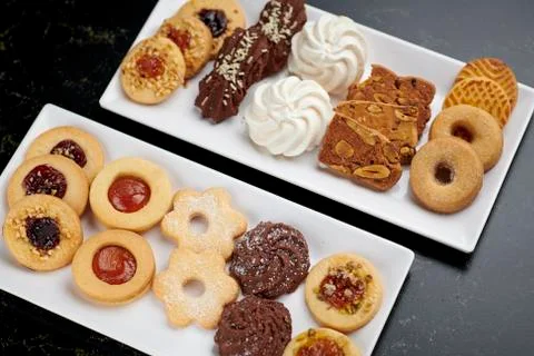 Two white plates of small different pastries Stock Photos