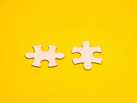 Two white puzzle pieces on a bright yellow background Stock Photos