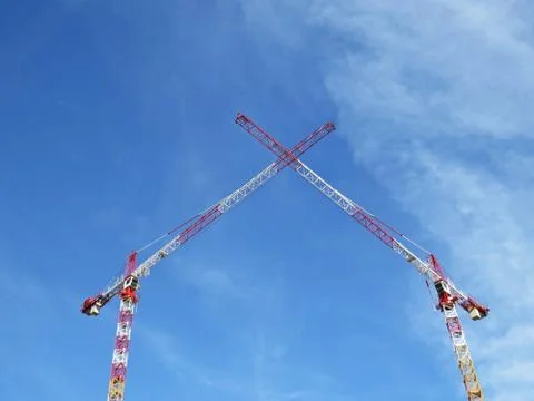 Two White Red Construction Tower Cranes Crossing their Arms on the Background Stock Photos