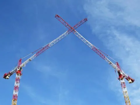 Two White Red Construction Tower Cranes Crossing their Arms on the Background Stock Photos