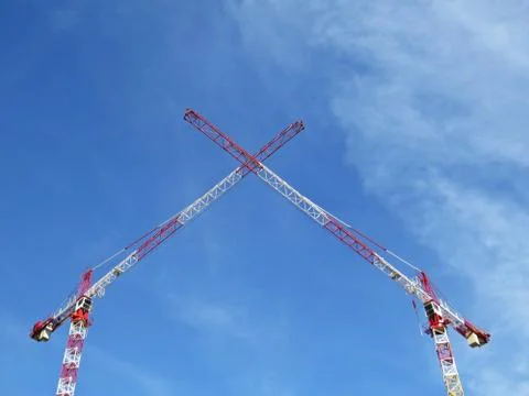 Two White Red Construction Tower Cranes Crossing their Arms on the Background Stock Photos