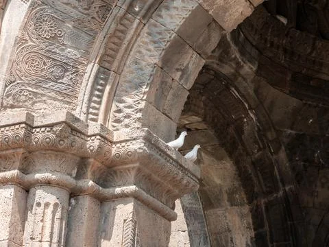Two white rock doves sit on ancient stone arch with carved details Stock Photos