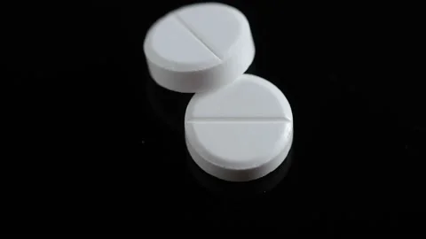 Two white round pills on a black background. white medical pills rotating Video stock 169777647