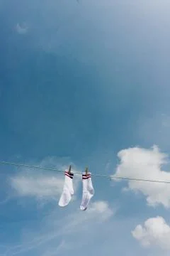 Two White Socks With Two Violet Stripes Hanging In the Sun Against Blue Sky W Stock Photos