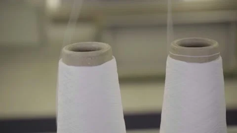 Two white spools with wire being taken from knitting machine, slow motion Stock Footage 153043876