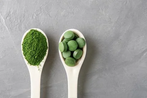 Two white spoon with chlorella or spirulina on a grey concrete background. To 写真素材