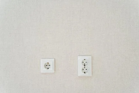 Two white wall sockets shaped like rectangles hang on the white wall Foto stock