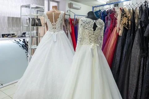 Two white wedding dresses on a background of dark evening dresses Stock Photos