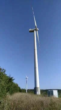 Two white wind generators set against blue sky Stock Photos