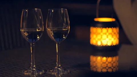 Two white wine wineglasses with  lantern with lighted candle on table. Video stock 90367049
