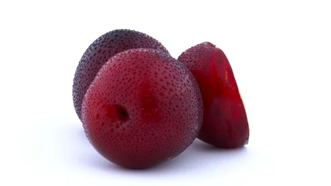 Two whole and one half cut purple maynard plums with water drops rotating Stock Footage 93633911