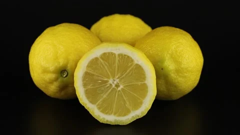 Two whole and two halves lemons rotates on a black background. Vidéo 151993215