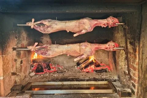 Two whole lambs roasting on a spit over an open fire Stock Photos