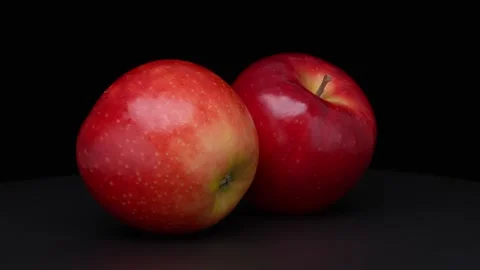 Two Whole Red Apples Rotating Against a Black Background 動画素材 346474672