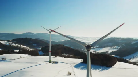 Two wind power generators in snow covered field aerial footage Stock Footage 342940189