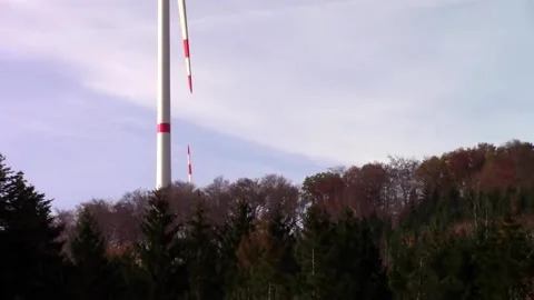 Two wind turbines standing on a forest hilltop Stock Footage 153549793