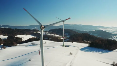 Two wind turbines standing in frozen field winter drone shot Stock Footage 343235592