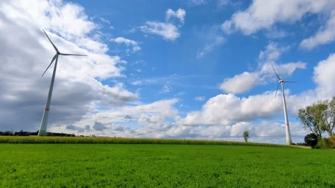 Two wind turbines standing on a green field under open sky. Stock Footage 317579895