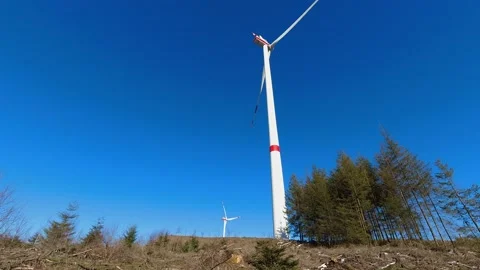 Two wind turbines timelapse turning in front of a sunny winter forest Stock Footage 171318084