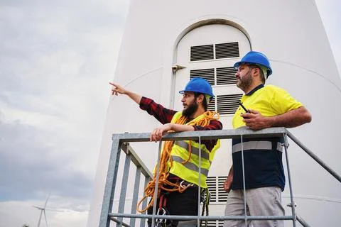 Two windmill engineer pointing to the turbine they have to do maintenance on Stock Photos