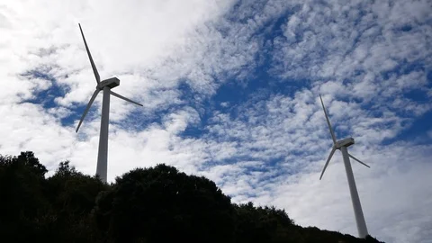 Two windmills spinning in the background of blue sky with clouds Video stock 113002723