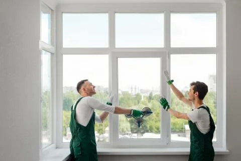 Two window installers replacing a window in the living room Stock Photos