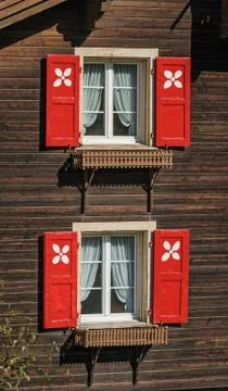 Two window with red shutters and white curtains in the wooden ho Stock Photos