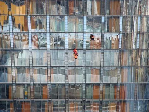 Two Window Workers on Skyscraper with Colorful Reflection Stock Photos